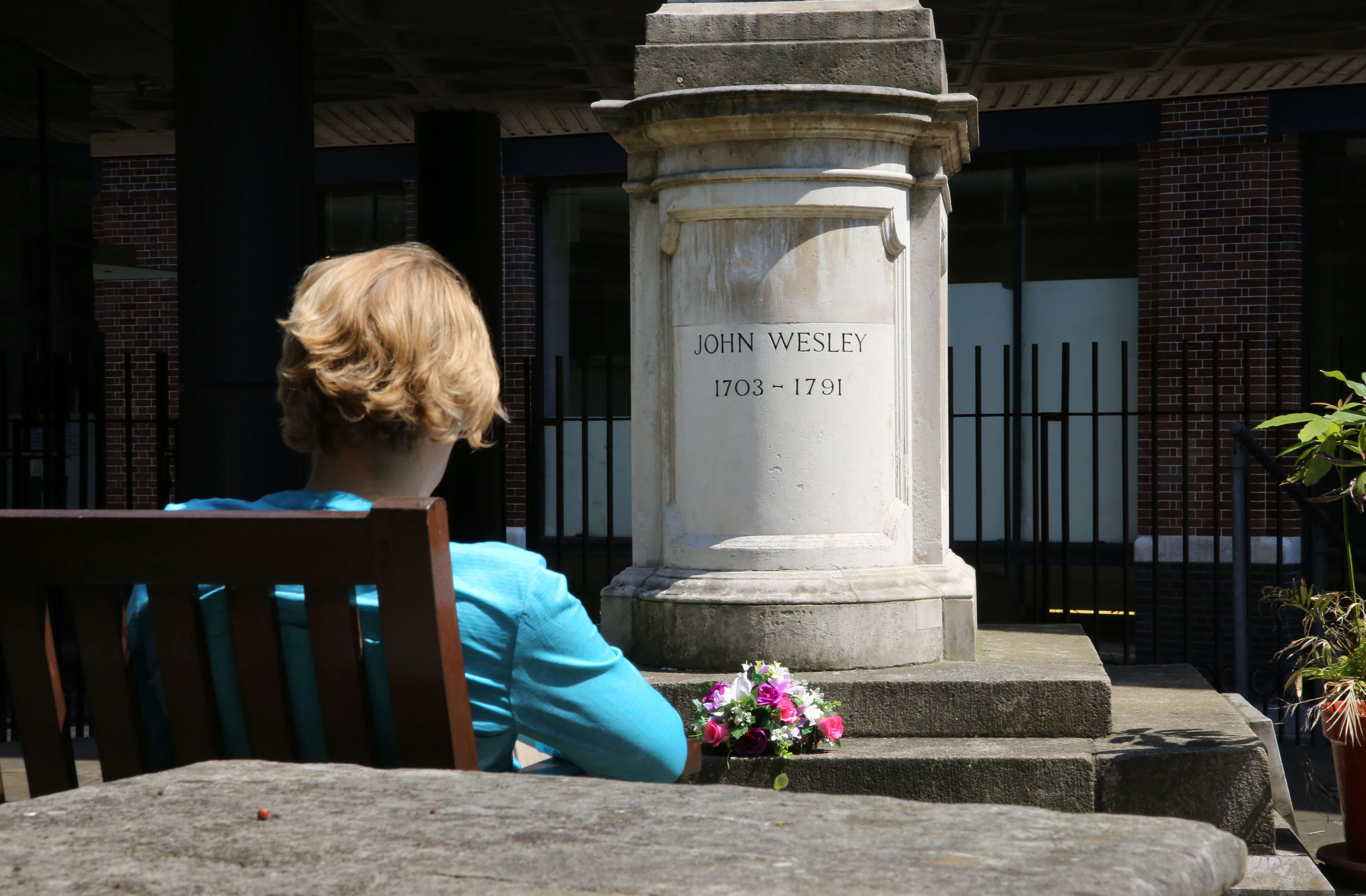 The tomb of John Wesley is located in a courtyard behind Wesley's Chapel in London. Sitting by the tomb is Shaliimar Holderly, one of the pilgrims of the 2016 Wesley Pilgrimage. Photo by Kathleen Barry, United Methodist Communications